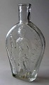 Pocket-Flasche 
in wei&szlig;em 
Glas, mit 
Relieffiguren 
geblasen. 19. 
Jahrhundert. 
Auf der einen 
...