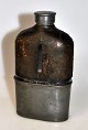 Englische 
Taschen flasche 
aus Glas, 19. 
Jh. Mit Leder, 
Zinnboden und 
Schraubverschluss.
 H: 15 cm.