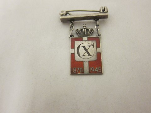 Kongemærket (Königabzeichen) aus Sterling Silber 925S mit rotem Email-Motiv von 
Dannebrog
Diese Model ist eine Brosche mit einem Balken
Jahr 1870-1945 und Christian X.
Die Georg Jensen Silberschmiede hat sie produciert