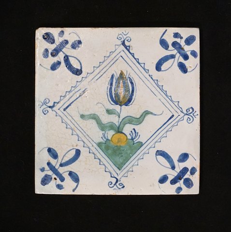 Polykromdekoreret hollandsk flise med 
tulipanmotiv. Cirka 1620-40. Mål: 13x13cm