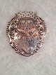 Silber-Emblem. 
Gravierte 
Brandselløbet 
02.10.21. 
Breite :: 7,5 
cm. - Größe: 
8,2 cm. ...