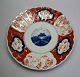 Imari Teller, 
Japan, 19. 
Jahrhundert. 
Polychrome 
Dekoration. 
Gelappt Rand. 
Dia:. 22 cm.