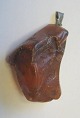 St&uuml;ck 
Bernstein, 
Rohmaterial, 
D&auml;nemark. 
Mit &Ouml;se in 
Silber. L:. 5 
cm. Gew. 12,9 
Gramm.