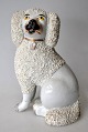 Staffordshire 
Pudelhund, 19. 
Jh. Weiße 
Fayence. Höhe: 
18 cm.