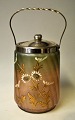 Kekseimer, ca. 
1900. 
Irisierend 
bemaltes Glas 
mit Emaildekor 
mit Blumen. 
Griff und 
Deckel aus ...