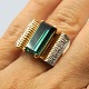 A gold ring set 
with a big 
facet cut green 
tourmaline and 
10 smal 
diamonds, 
mounted in 
white ...