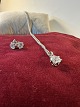 Halskette aus 
Sterlingsilber 
mit Anhänger 
und Ohrringen. 
Der Anhänger 
hat weiße 
Saphirsteine. 
...