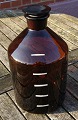 Large and well-maintained 5 liter apothecary bottle with pouring spoutin in dark brown glass. On the back there are liter measurements.